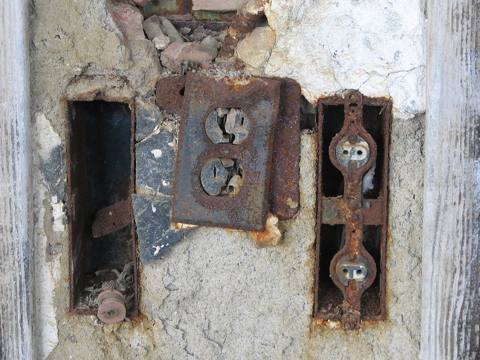rusted boxes, receptacles with no cover plates, crumbling wall