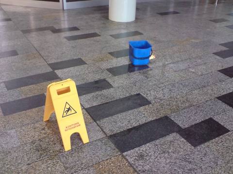water on a lobby floor, bucket and wet-floor sign