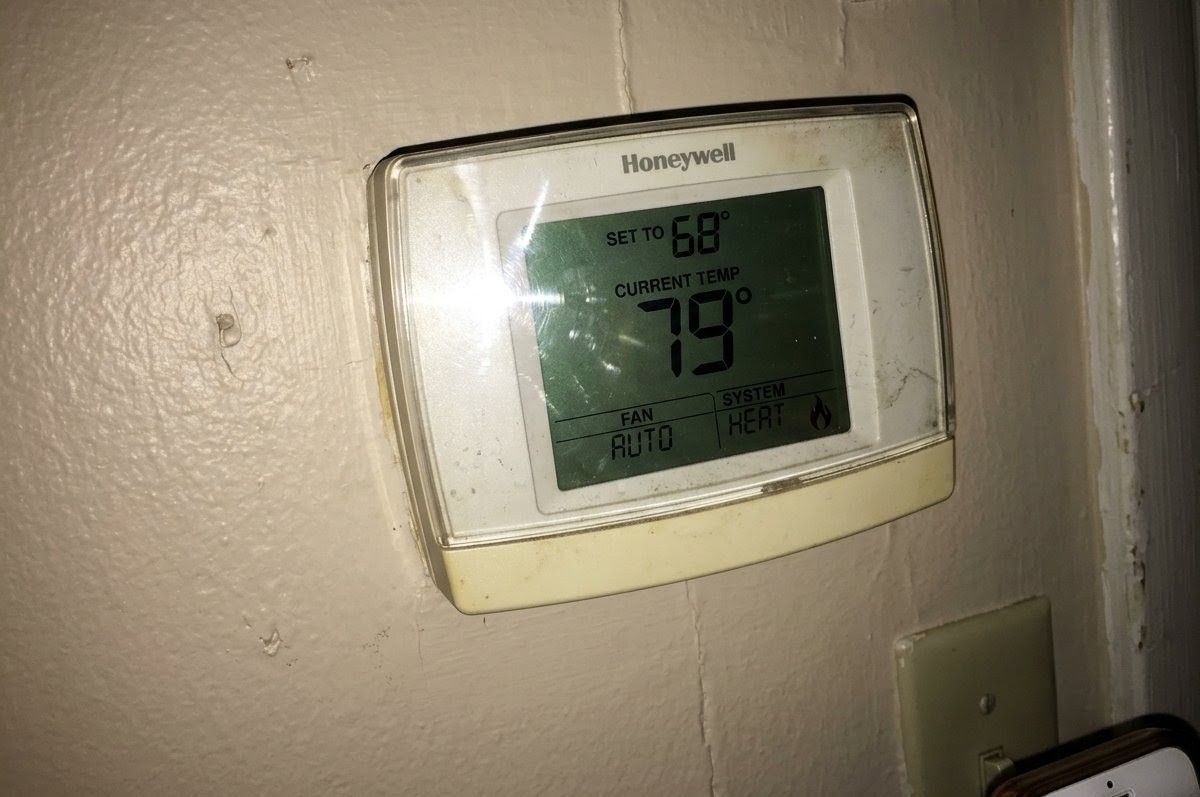 A wall thermostat set to 68 degrees while the room reads 79