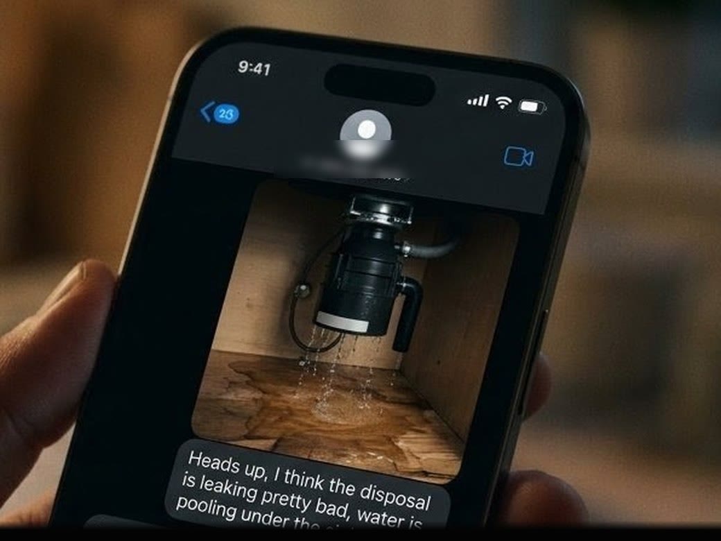 A phone showing a tenant's text: heads up, I think the disposal is leaking