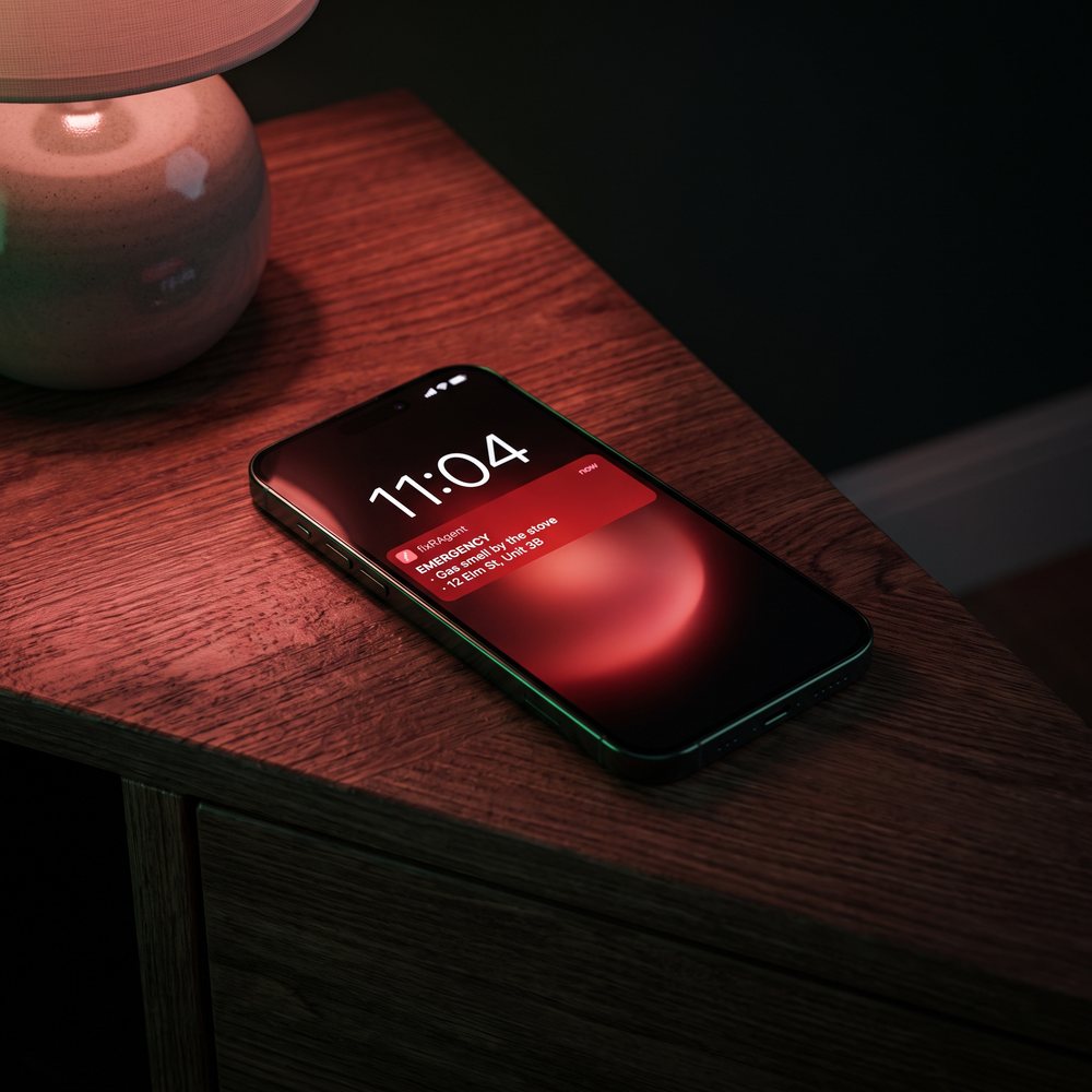 A phone on a nightstand at 11:04 showing an emergency email from fixRAgent