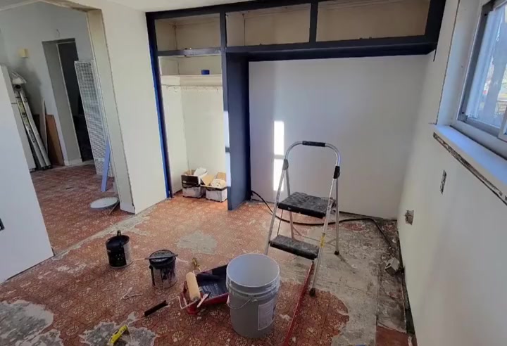 New walls up and painted, a step ladder and paint buckets on the floor
